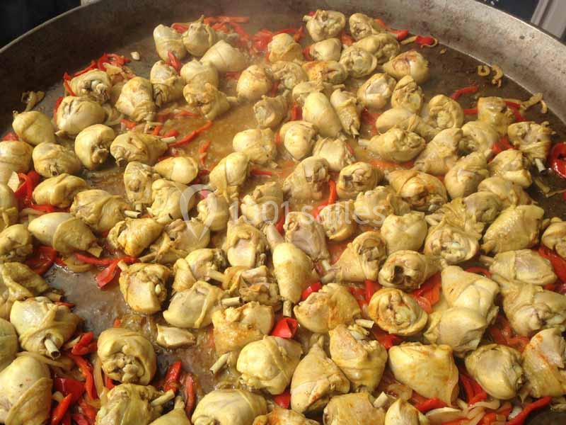 Poulet mijoté avec des poivrons rouges dans une grande poêle en métal.