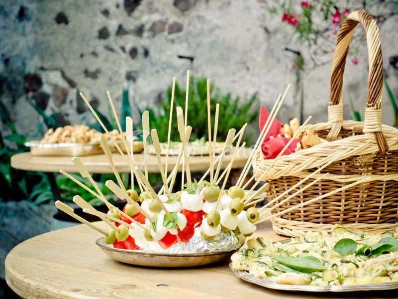 Assortiment de brochettes apéritives avec olives, tomates et fromage, disposé sur une table en extérieur.