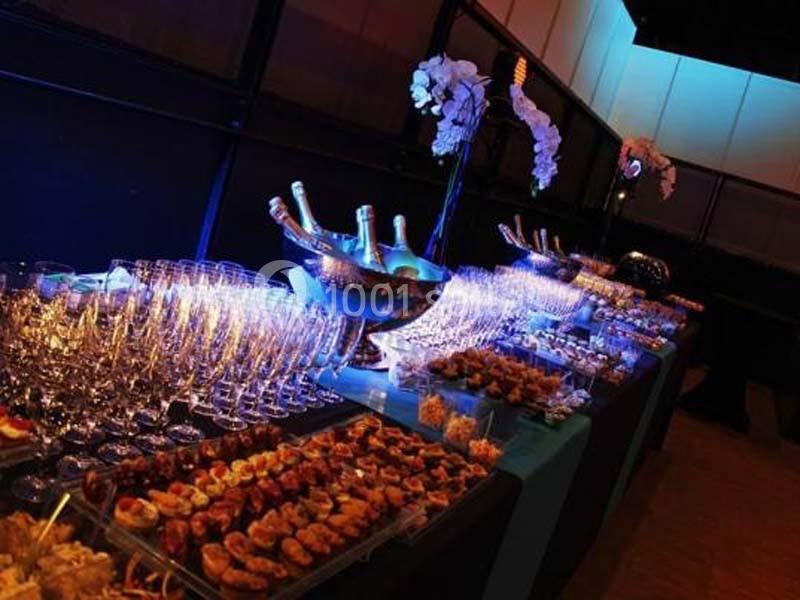 Table de réception élégamment dressée avec des coupes de champagne, des bouteilles et des amuse-bouches variés.