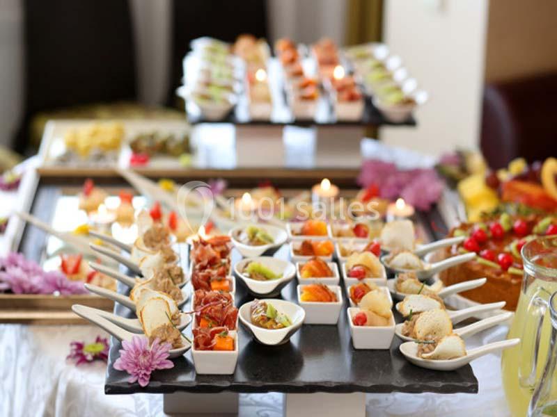 Plateau de verrines et amuse-bouches variés disposés sur une table décorée de fleurs.