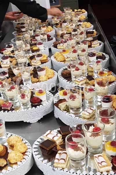 Plateaux garnis de verrines, pâtisseries et desserts variés disposés pour un buffet ou une réception.