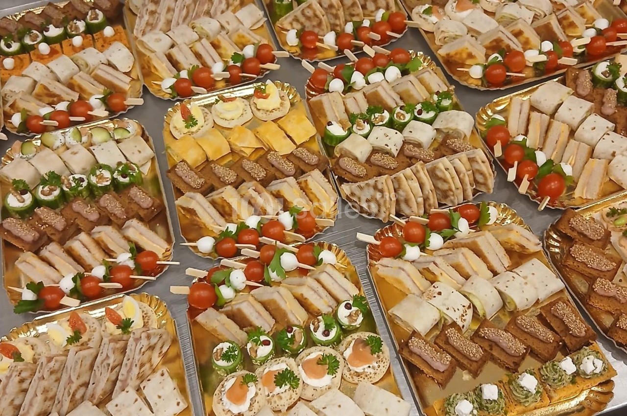 Plateaux garnis de divers amuse-bouches, incluant canapés, roulés, brochettes et mini-sandwichs.