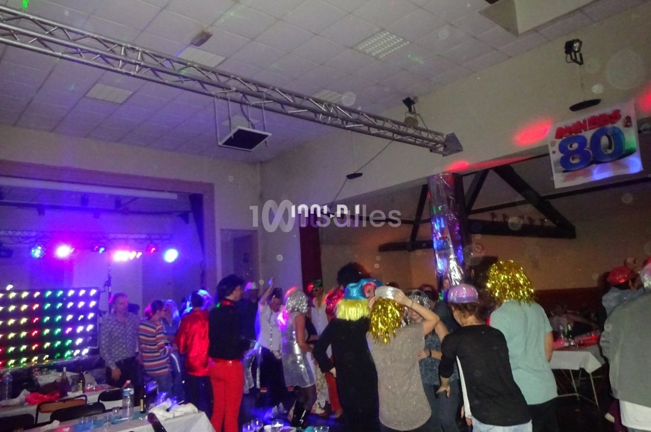Des personnes dansent et s'amusent lors d'une soirée festive avec éclairages colorés et décorations rétro.