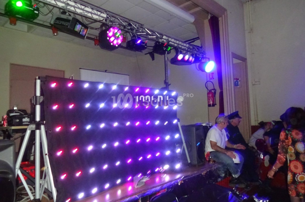 Éclairage coloré et panneau lumineux LED dans une salle avec des personnes assises à proximité.