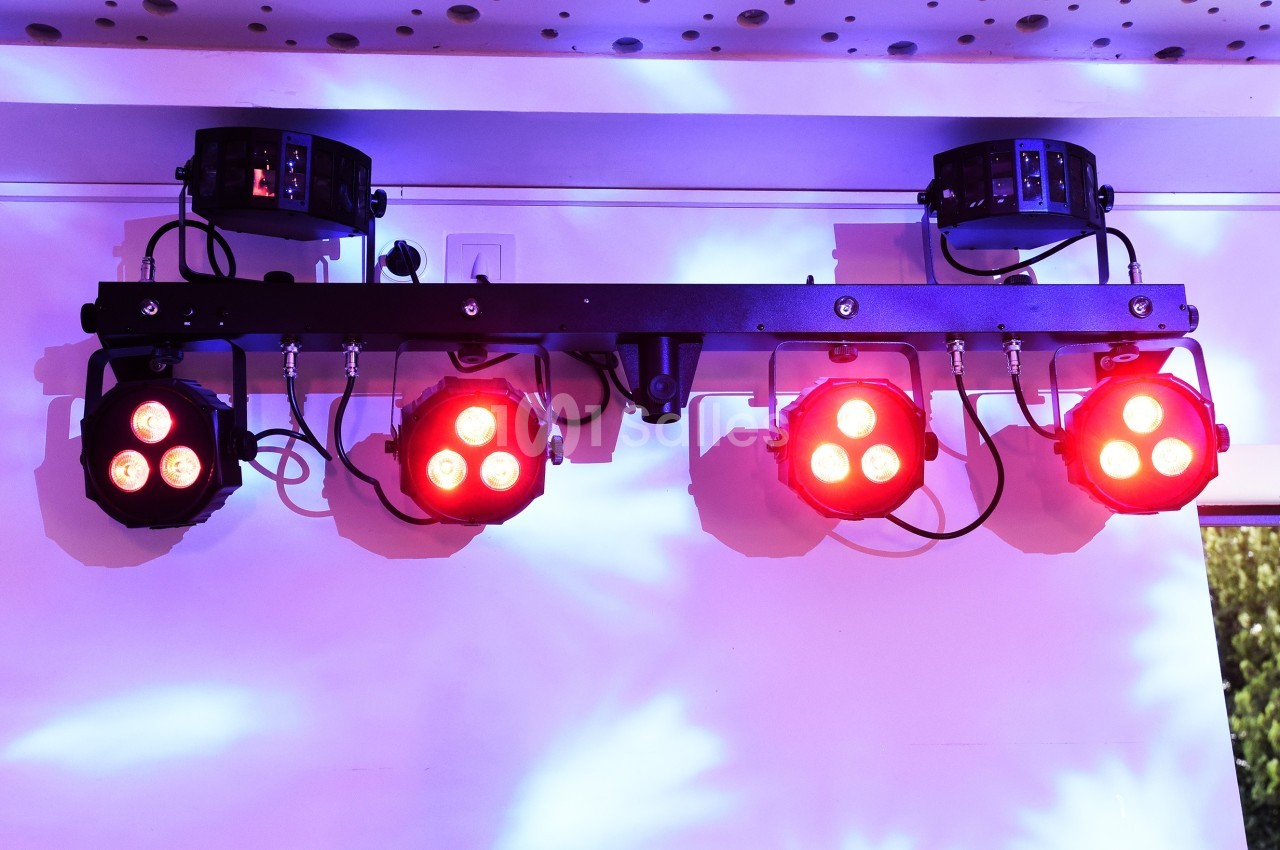 Projecteurs LED rouges fixés sur une barre métallique, éclairant un mur avec des reflets lumineux violets.