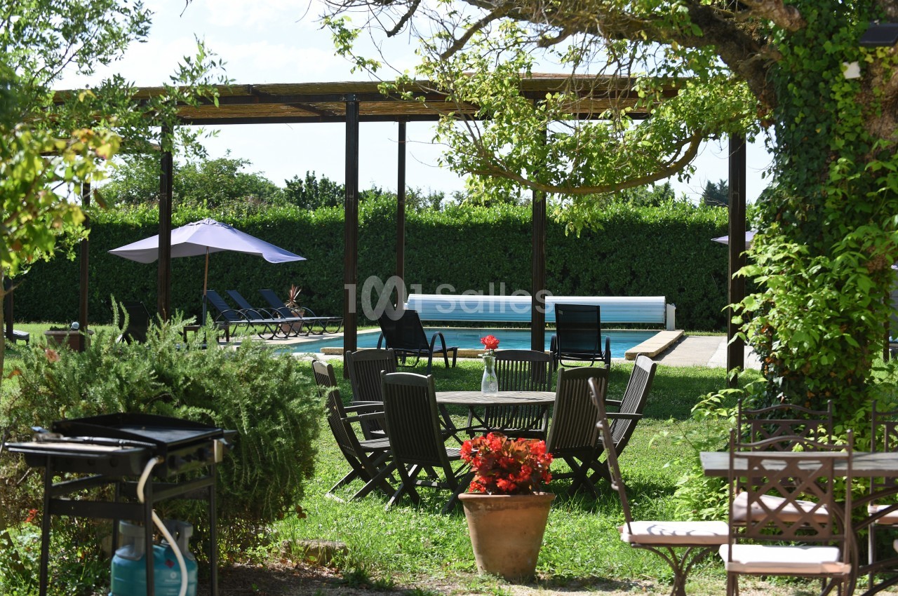 Mobilier de jardin en bois autour d'une table, près d'une piscine entourée de transats et de parasols dans un jardin…