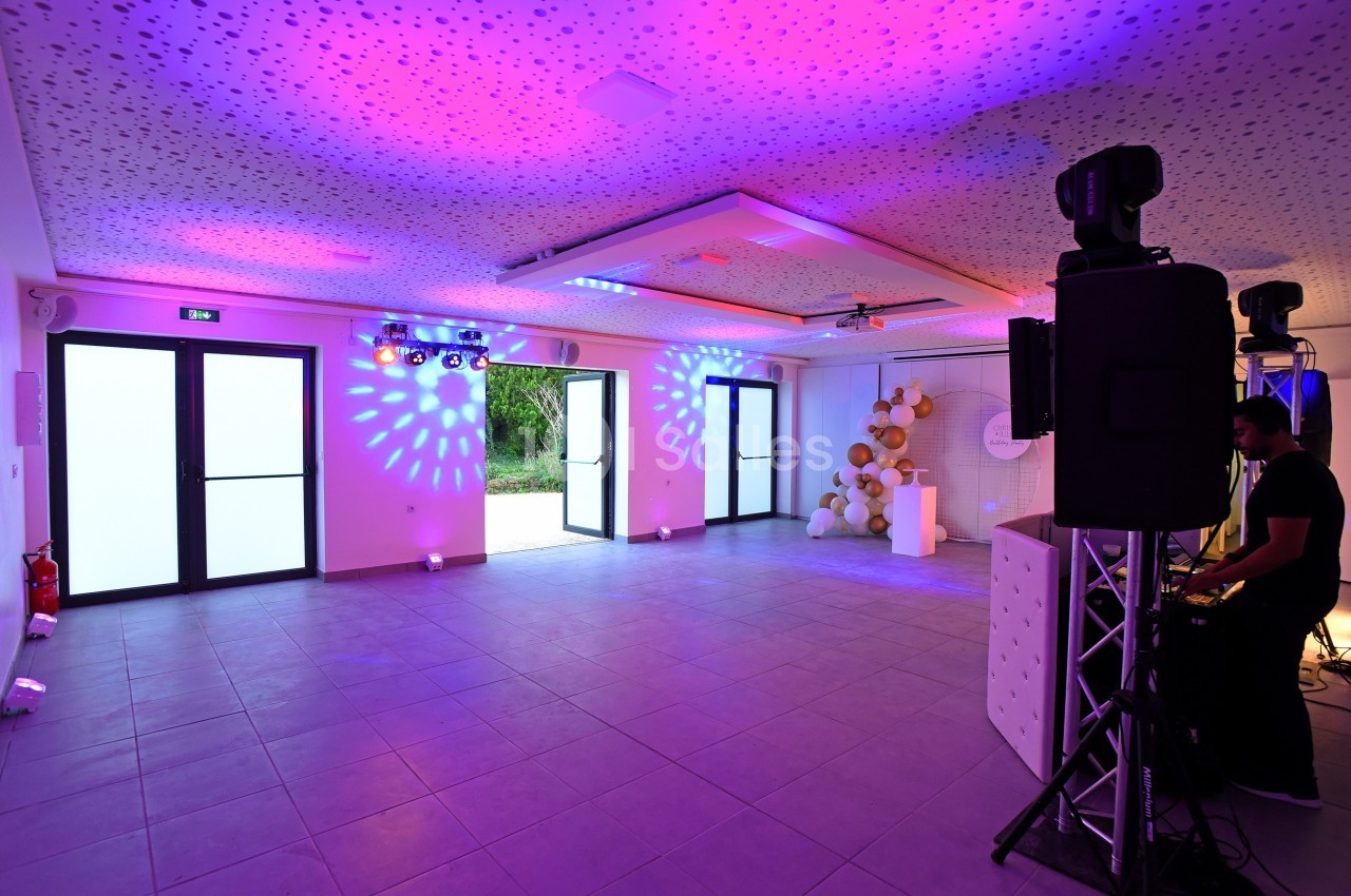 Salle de réception moderne avec éclairage coloré, équipement audio et décorations murales en ballons.