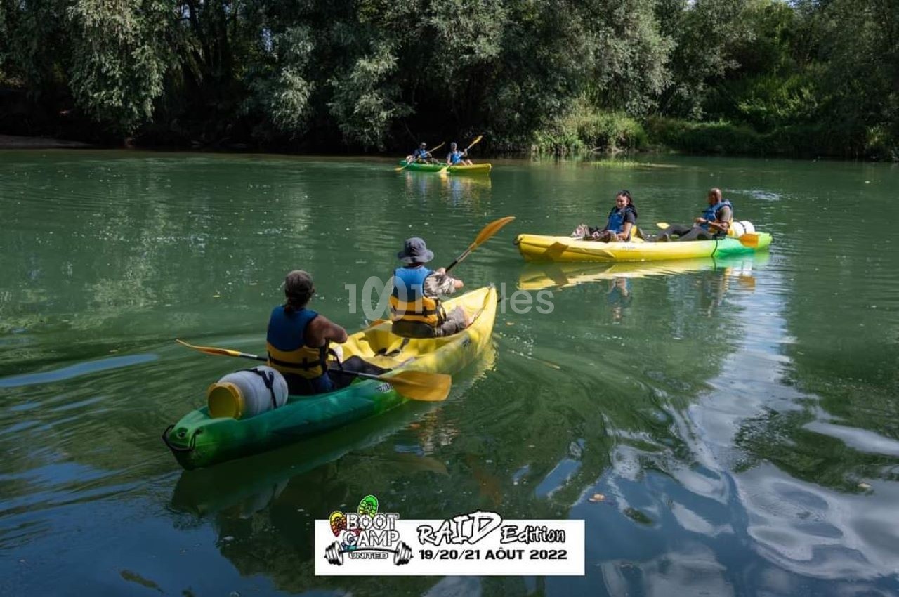 Des personnes pagayant en canoë sur une rivière entourée de végétation dense par une journée ensoleillée.