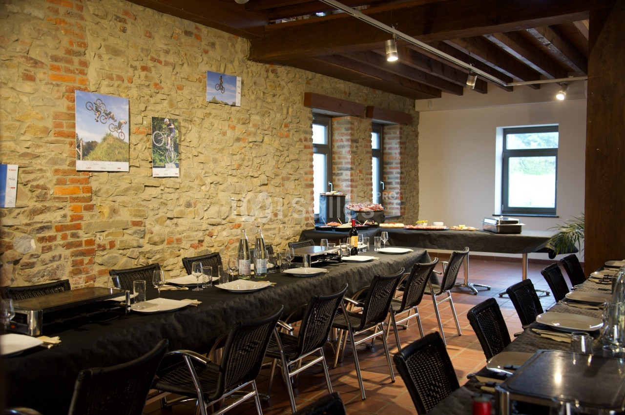 Salle à manger avec murs en pierre, tables dressées pour un repas et buffet installé près des fenêtres.