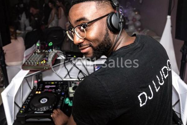 Un DJ portant un casque audio mixe sur une table de mixage lors d'un événement festif.
