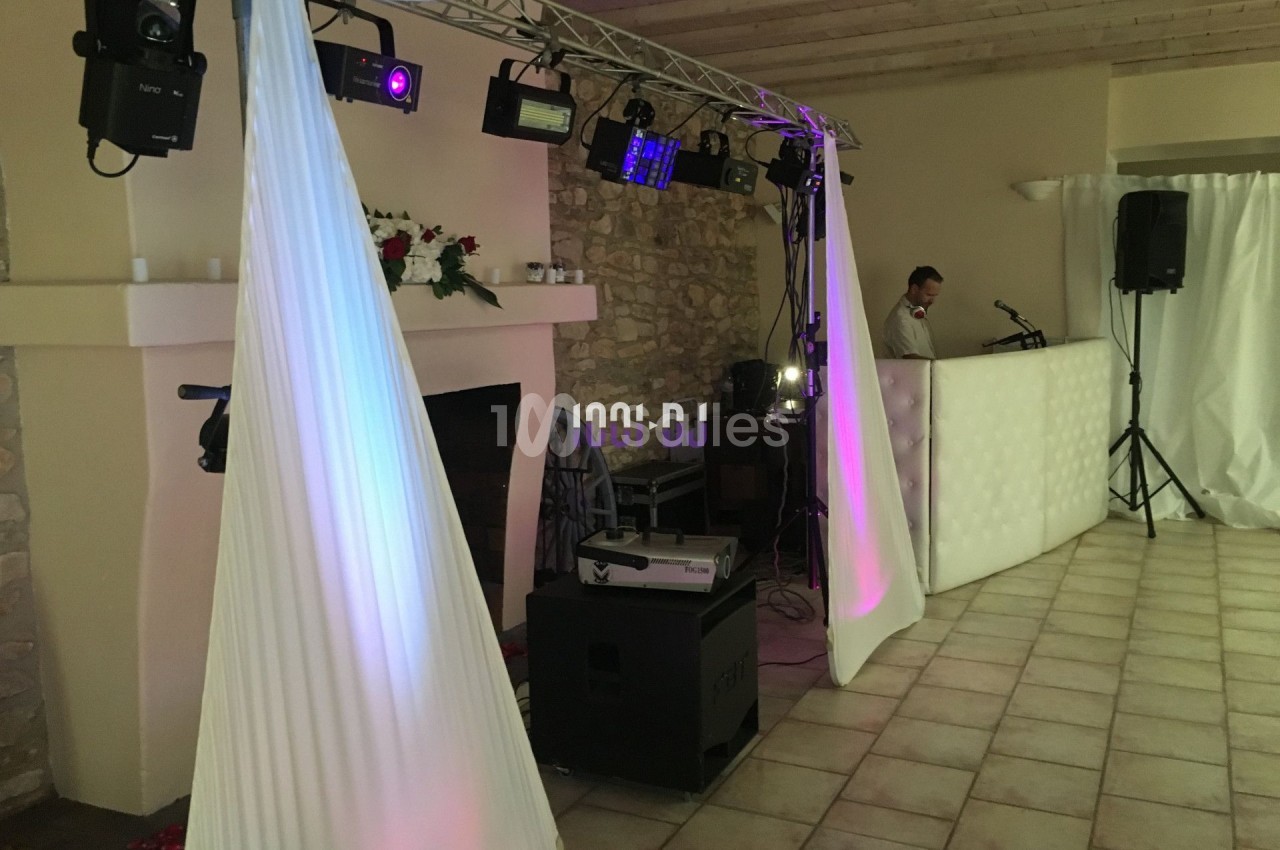 Installation de matériel d'éclairage et sonorisation dans une salle avec murs en pierre et plafond en bois.