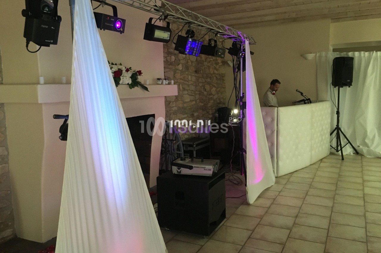Installation de matériel d'éclairage et sonorisation dans une salle avec murs en pierre et plafond en bois.