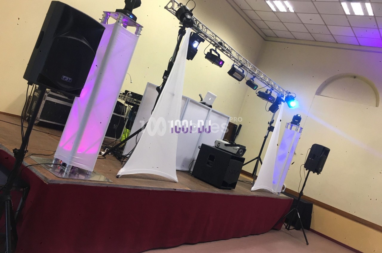 Installation de matériel de sonorisation et éclairage sur une scène dans une salle intérieure.