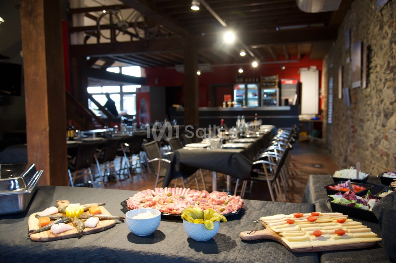 Buffet avec charcuterie, fromage, légumes et salades, dans une salle de réception au décor rustique.