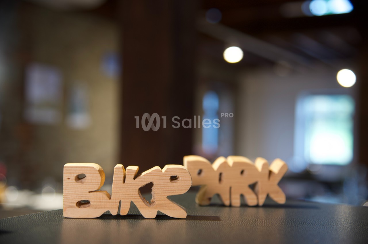 Sculptures en bois formant les mots ’Bike Park’ posées sur une surface sombre dans un intérieur flou.