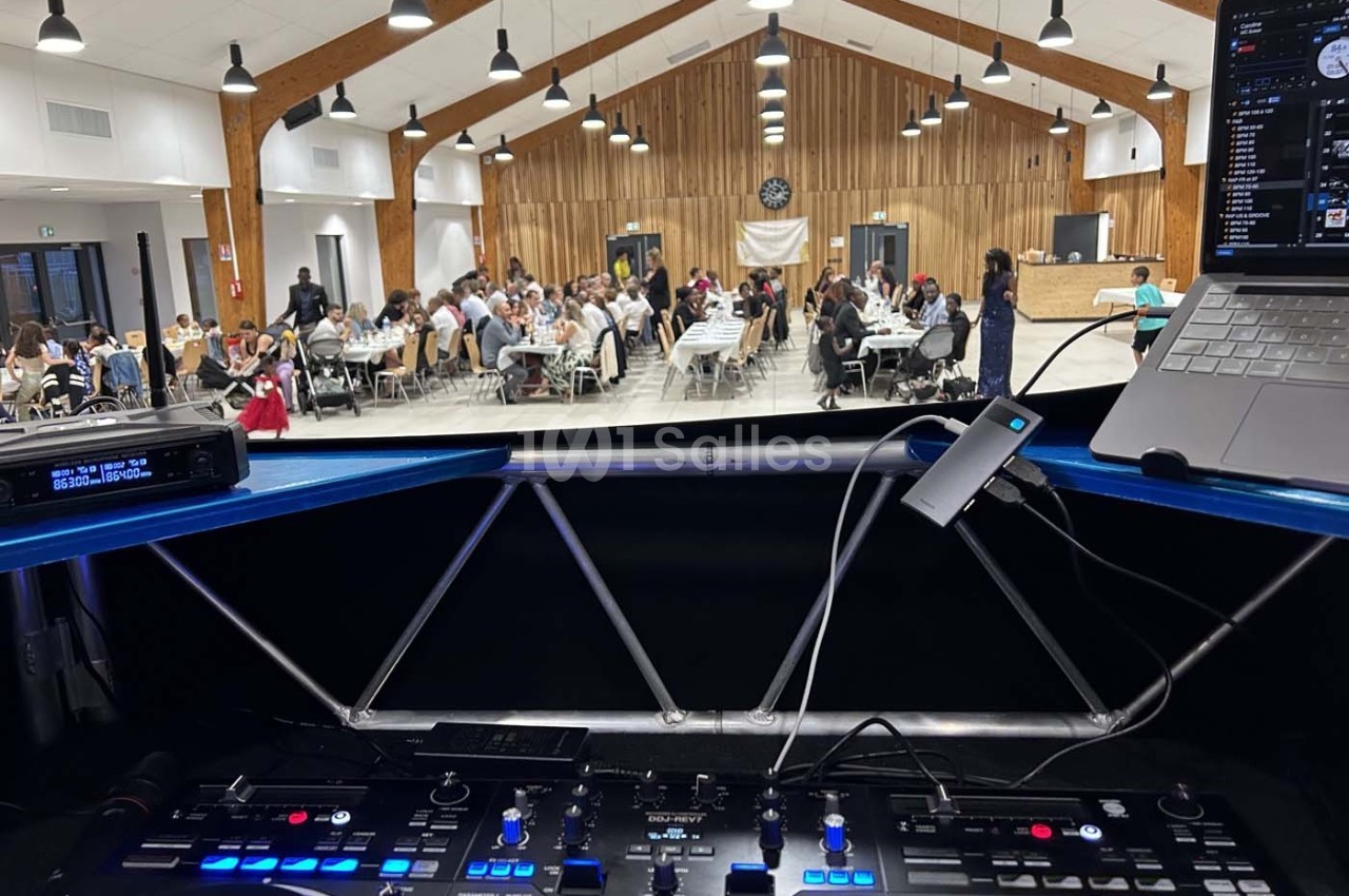 Vue depuis une table de mixage sur une salle de réception animée, avec des invités assis à des tables.