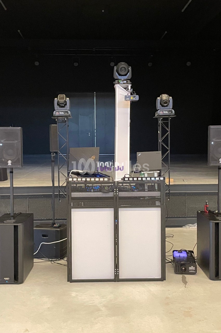 Équipement de sonorisation comprenant enceintes, projecteurs et consoles, installé sur une scène vide.