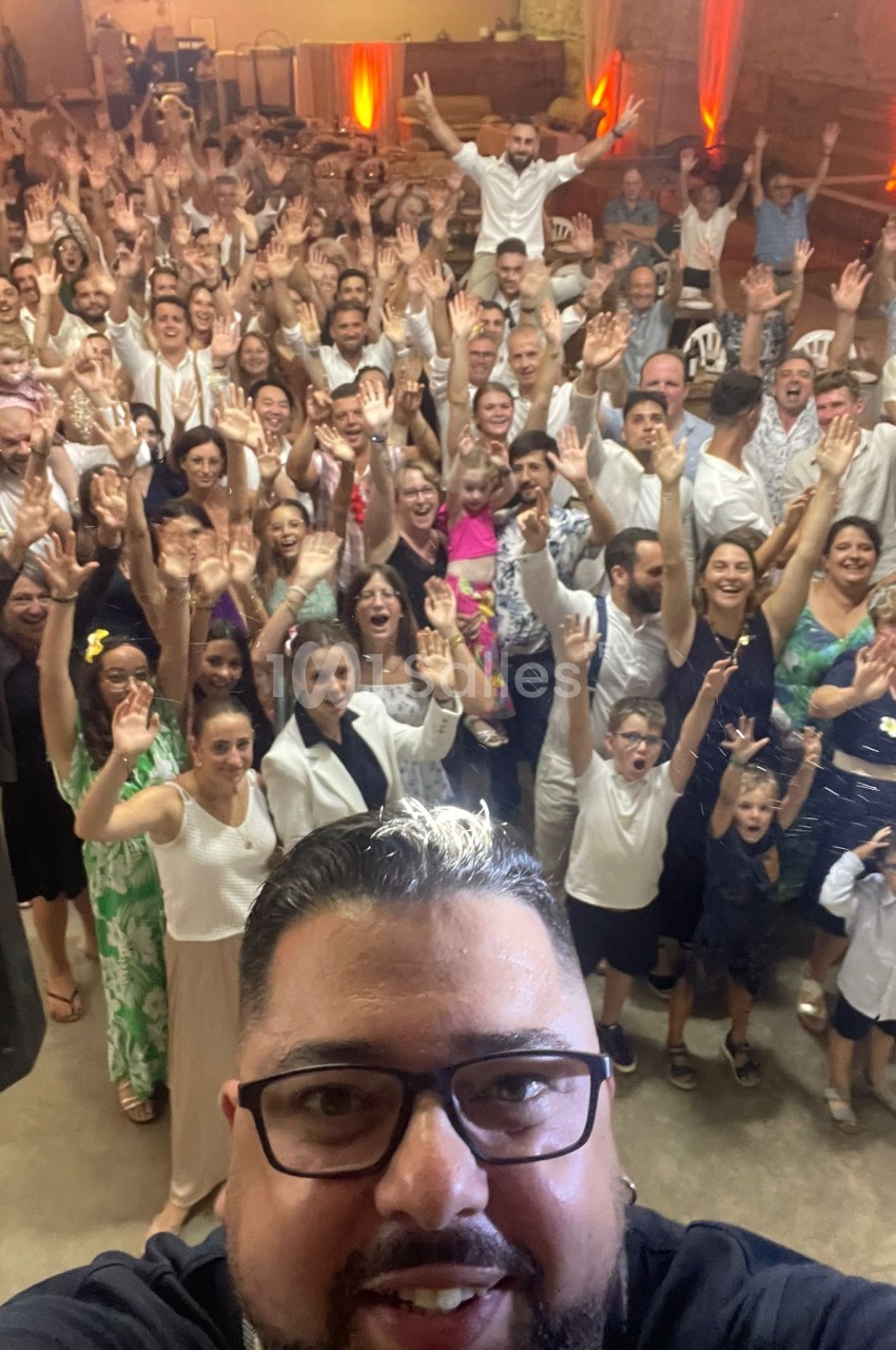 Un groupe de personnes souriantes levant les bras lors d'un événement festif dans une salle éclairée.