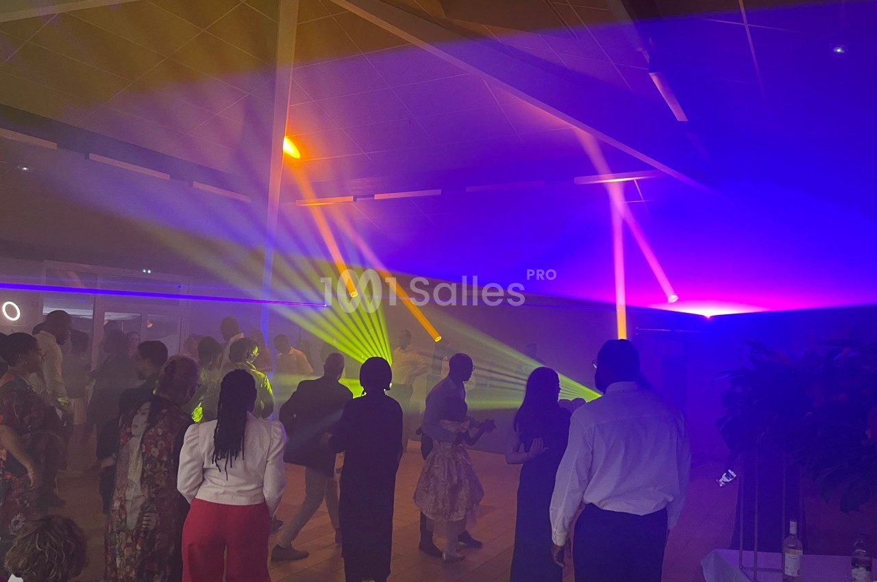 Groupe de personnes dans une salle sombre avec des jeux de lumière colorés et une ambiance festive.