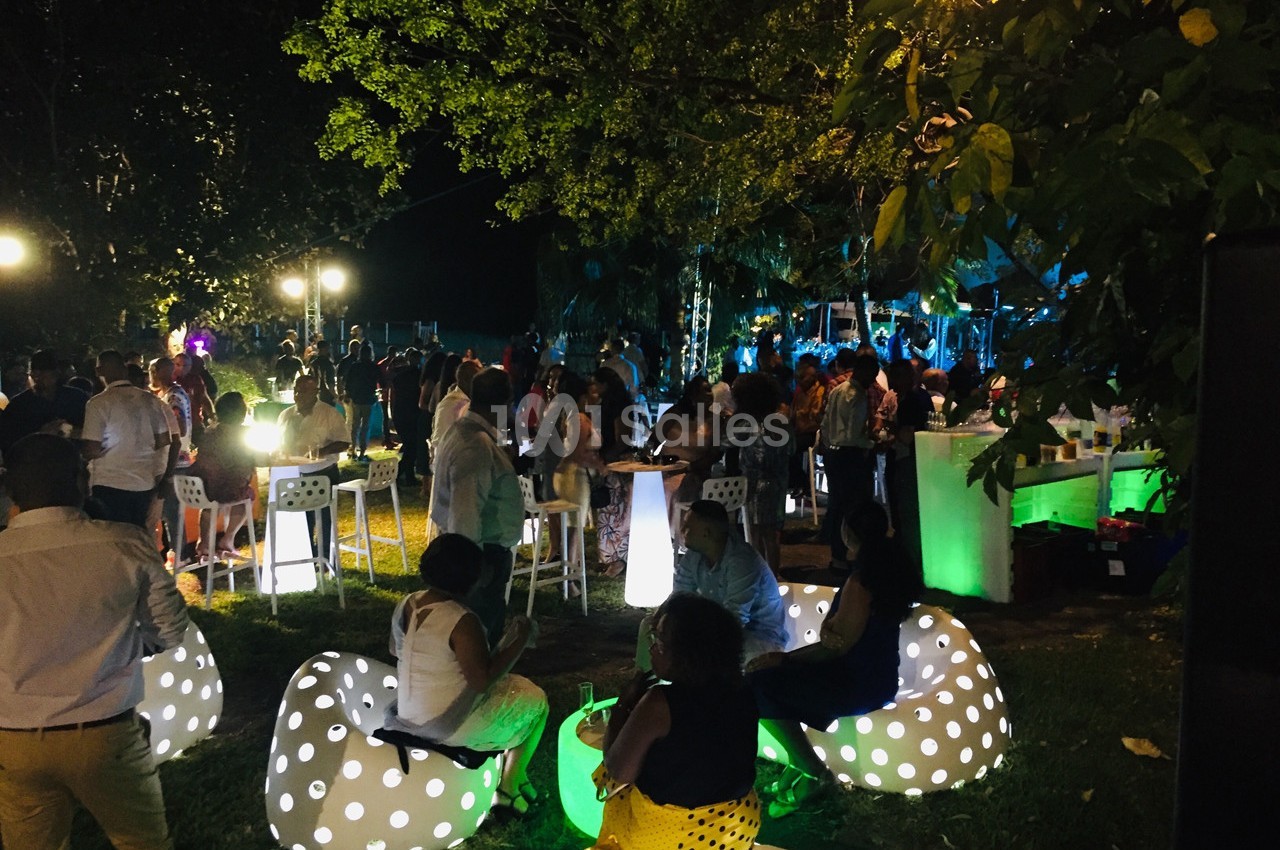 Groupe de personnes réunies en soirée extérieure, éclairée par des lumières colorées et des sièges lumineux.
