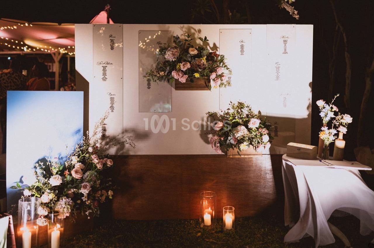 Décoration florale avec bougies et panneaux blancs, disposée en extérieur sous un éclairage tamisé.