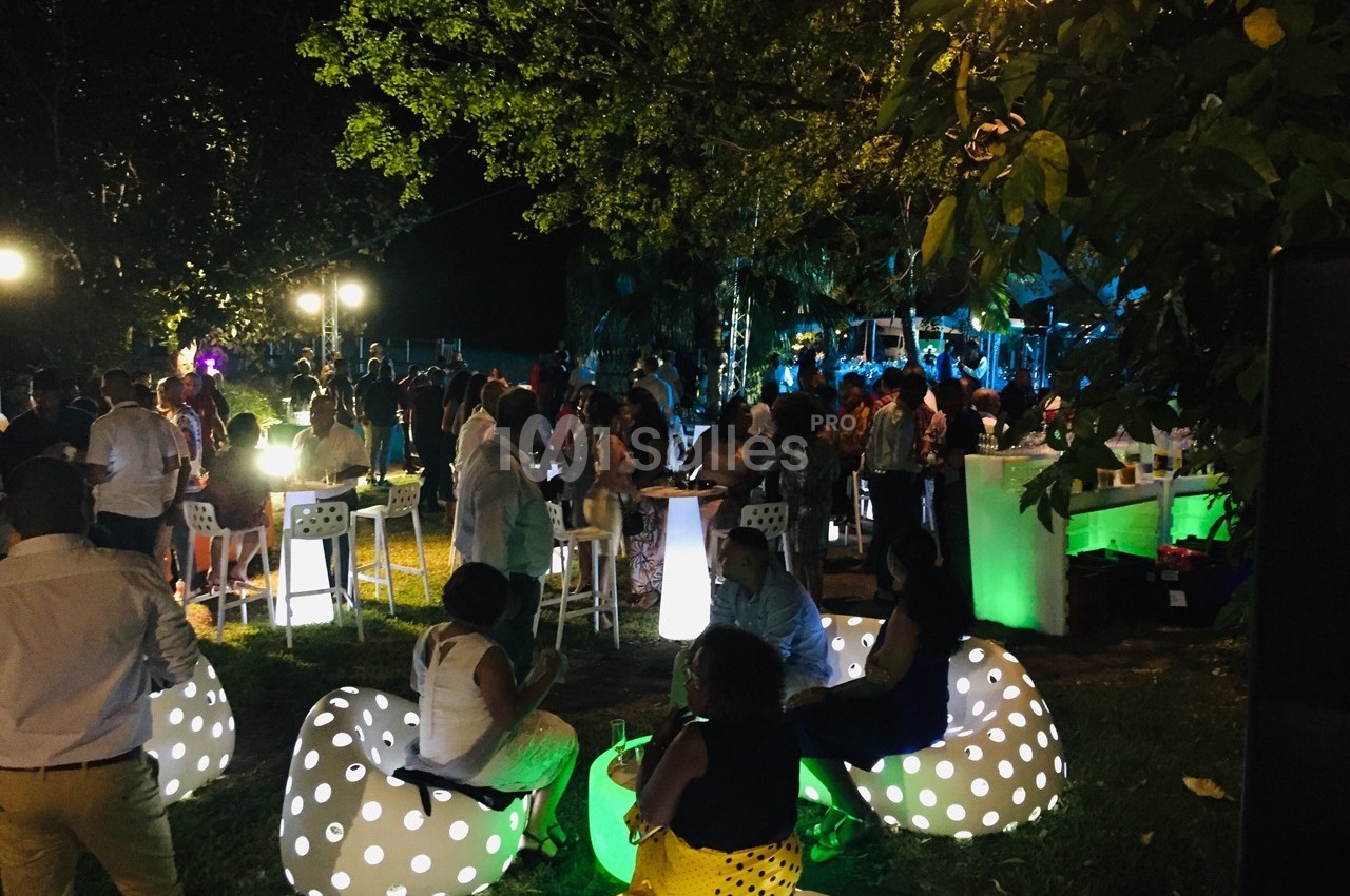 Groupe de personnes réunies en soirée en plein air, éclairées par des lumières colorées et des sièges lumineux.