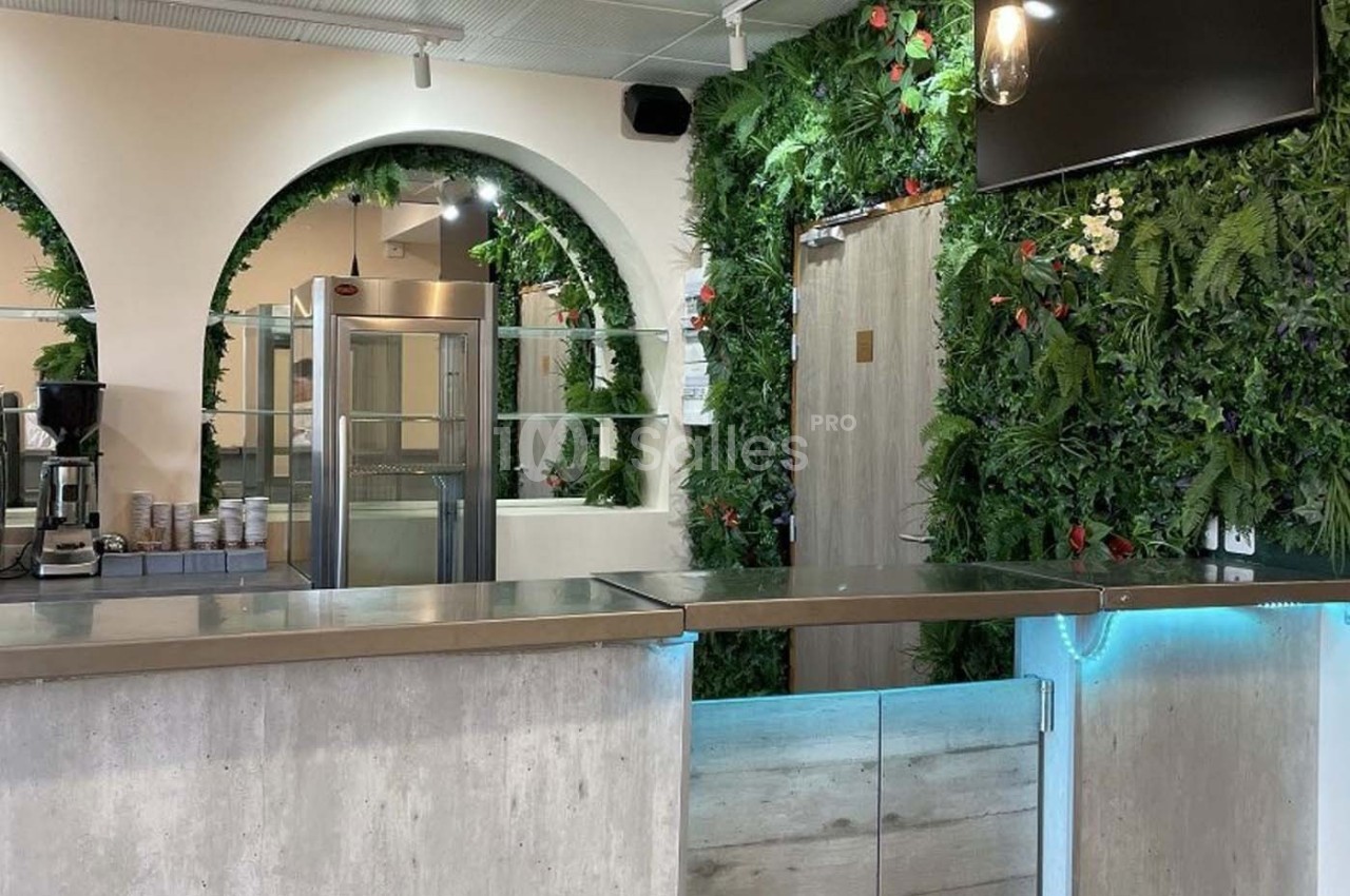 Comptoir moderne dans un espace lumineux avec murs ornés de plantes vertes et arches décoratives.