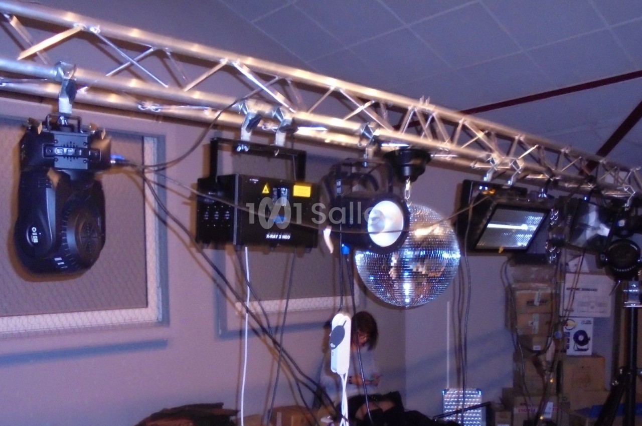 Équipement d'éclairage et de projection suspendu sur une structure métallique dans une salle intérieure.