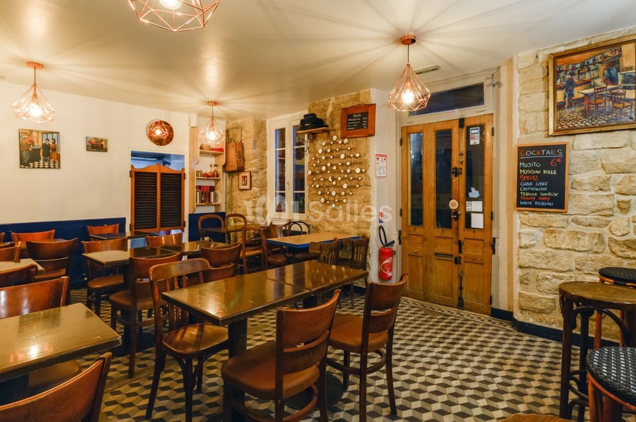 Salle de restaurant avec tables en bois, chaises assorties, murs en pierre et éclairage chaleureux.