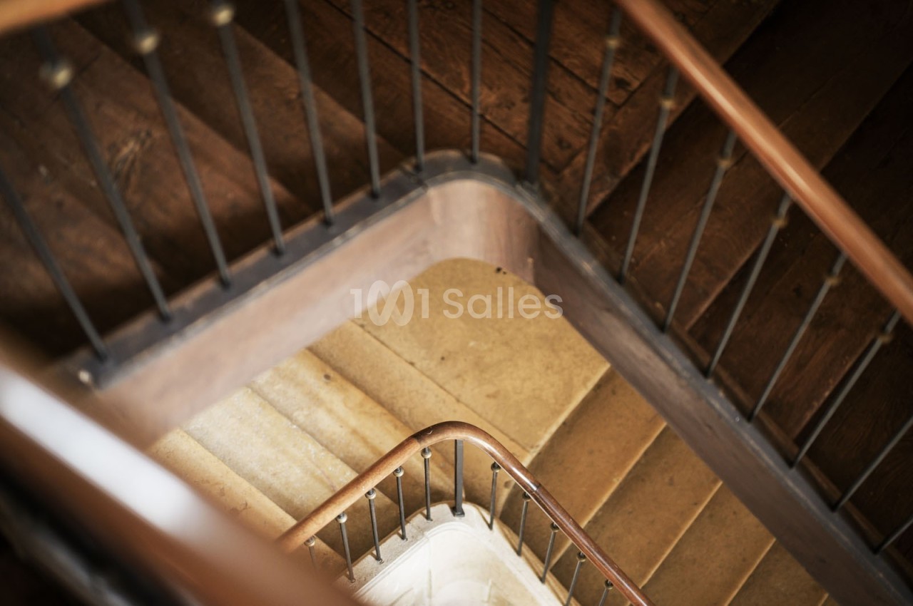 Escalier en colimaçon vu de dessus, avec des marches en pierre et une rampe en bois.