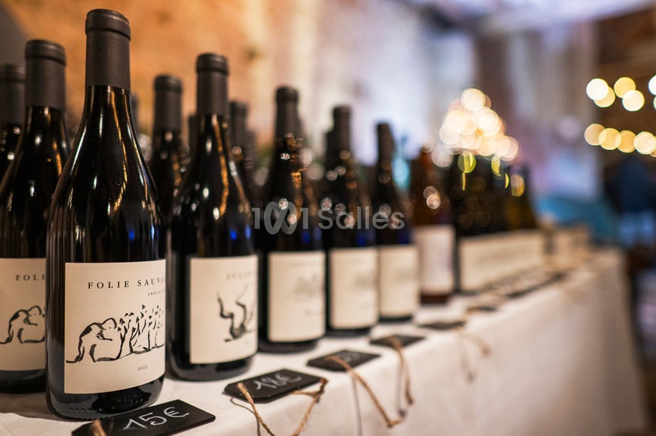 Bouteilles de vin alignées sur une table blanche avec étiquettes de prix visibles au premier plan.