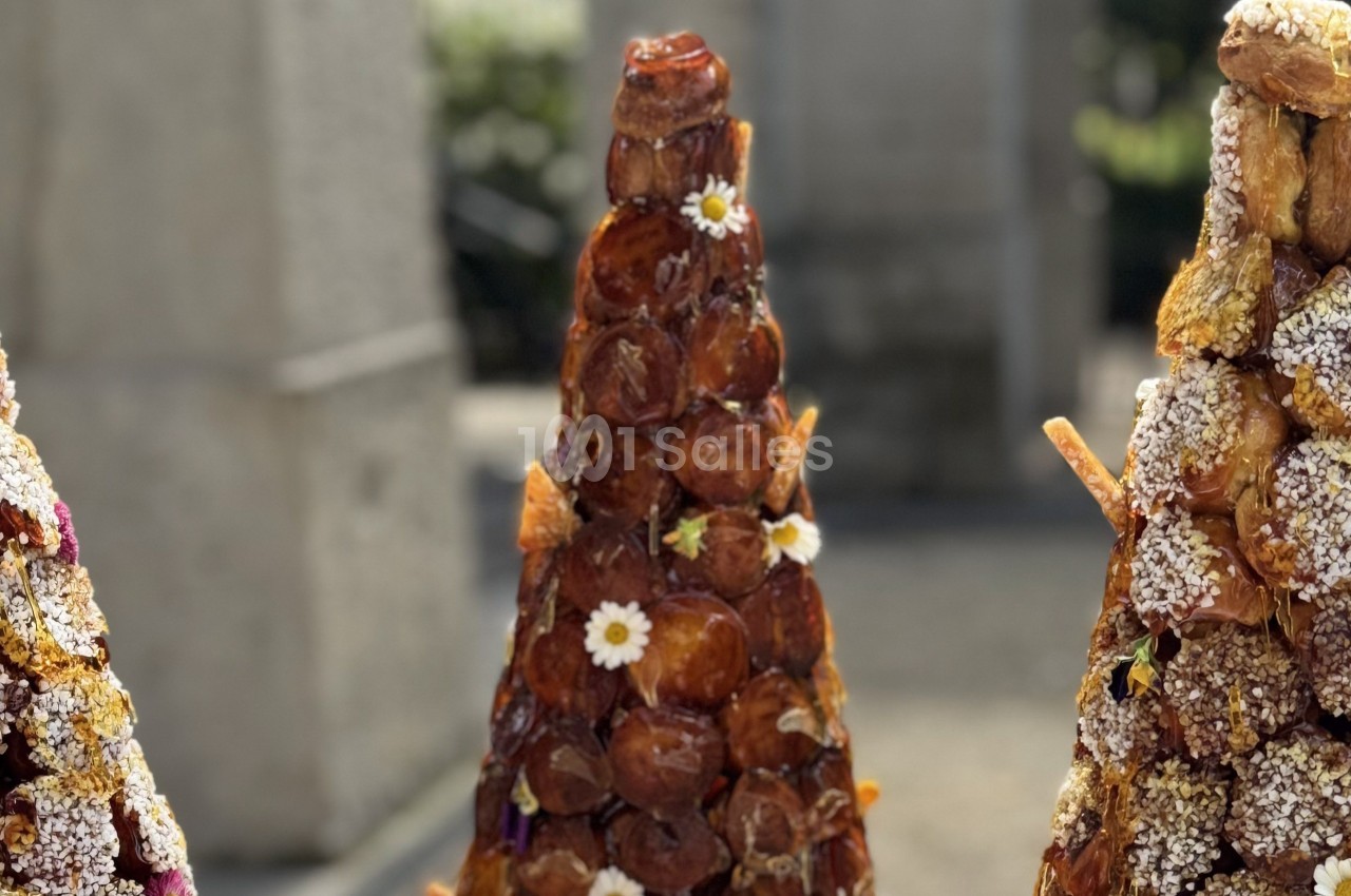 Trois croquembouches décorés de fleurs et de sucre, exposés en extérieur sous une lumière naturelle.