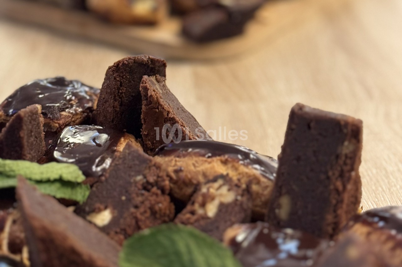 Assortiment de brownies au chocolat, certains nappés de glaçage, décorés de feuilles de menthe sur une table en bois.
