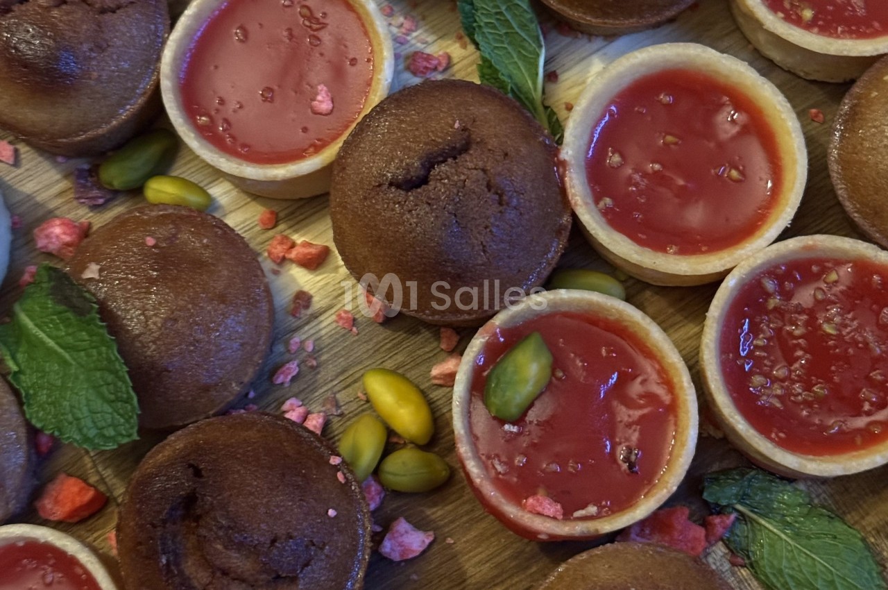 Assortiment de tartelettes au chocolat et à la framboise, décorées de pistaches, menthe et éclats de fruits.