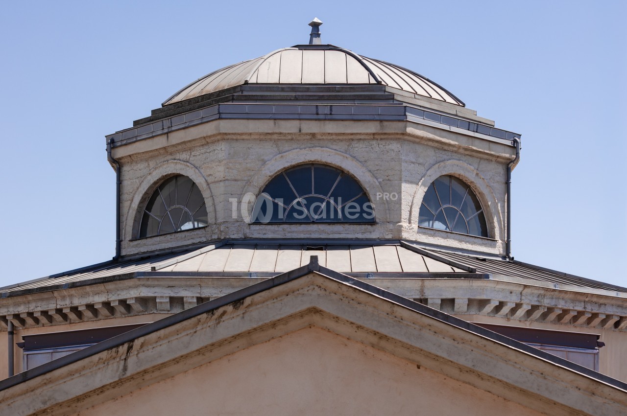 Dôme octogonal avec fenêtres cintrées et toit en métal, surmontant un bâtiment à façade triangulaire.