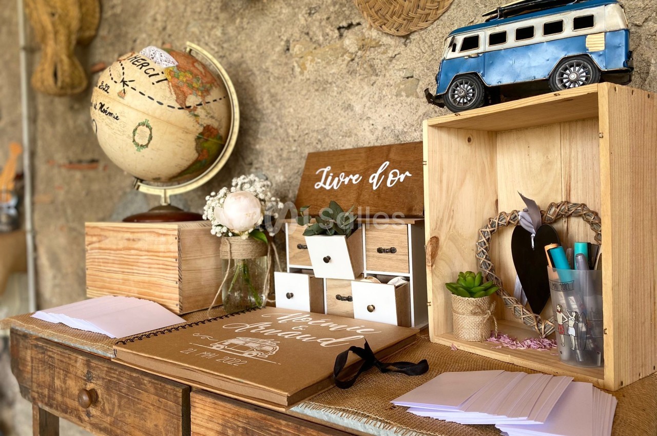 Décoration de table avec un globe terrestre, un livre d'or, des boîtes en bois et une miniature de van rétro.