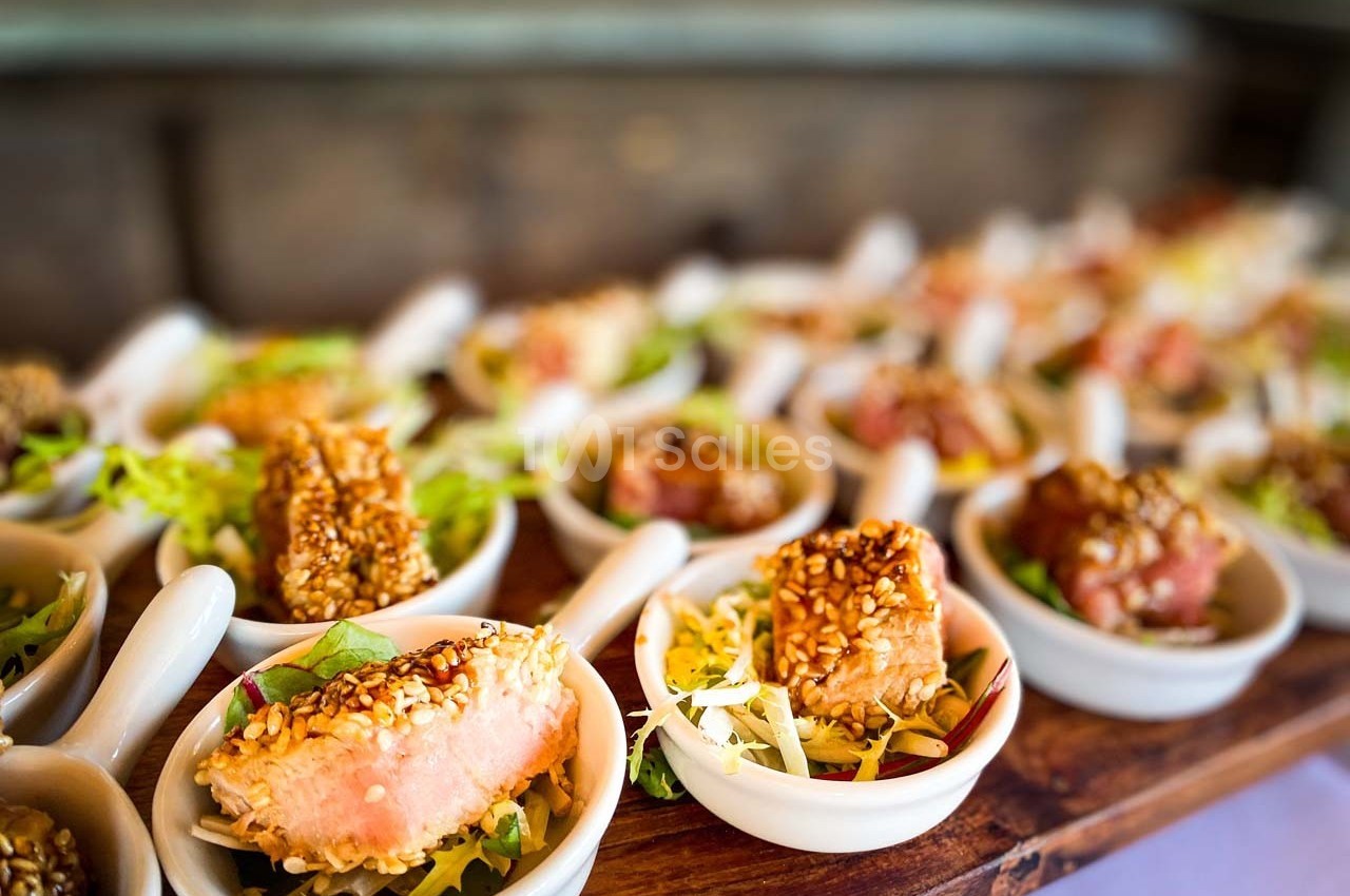 Petites portions de thon en croûte de sésame servies sur des cuillères avec une garniture de salade.
