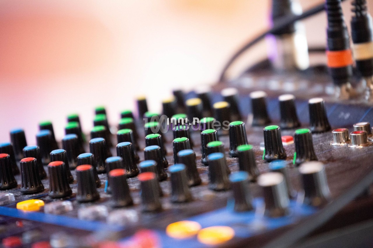 Table de mixage audio avec de nombreux boutons et curseurs colorés, utilisée pour régler le son.
