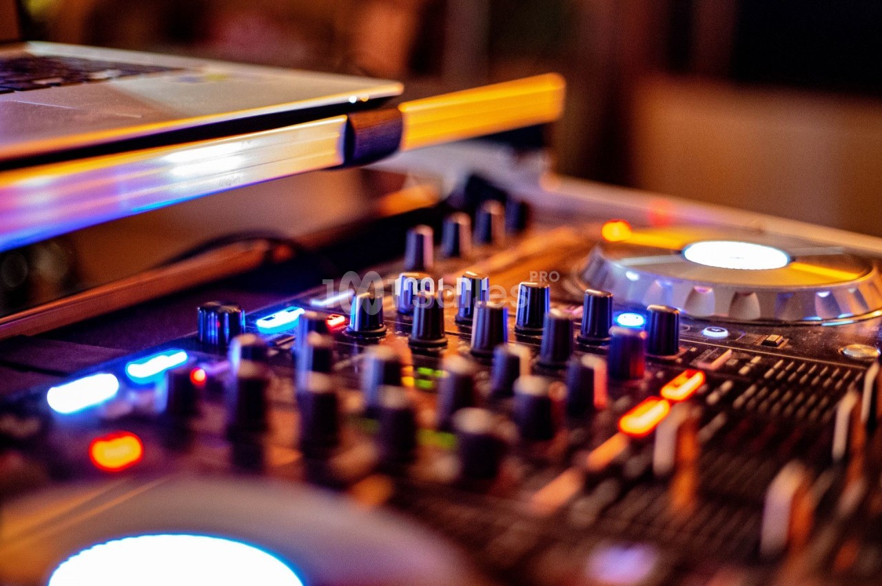 Table de mixage avec boutons, curseurs et éclairage coloré, utilisée pour le mixage audio.