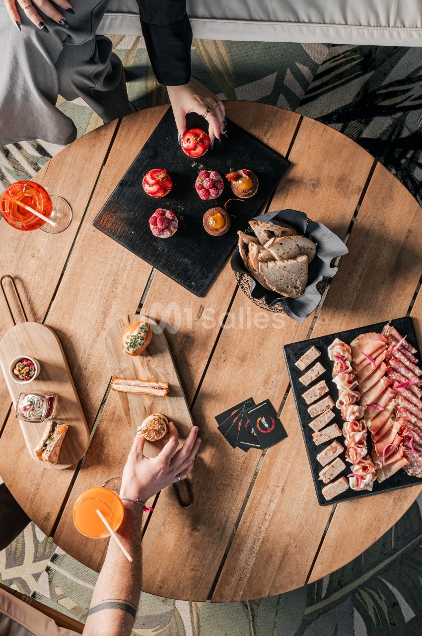 Vue de dessus d'une table en bois avec des planches apéritives, tapas variés et boissons colorées.