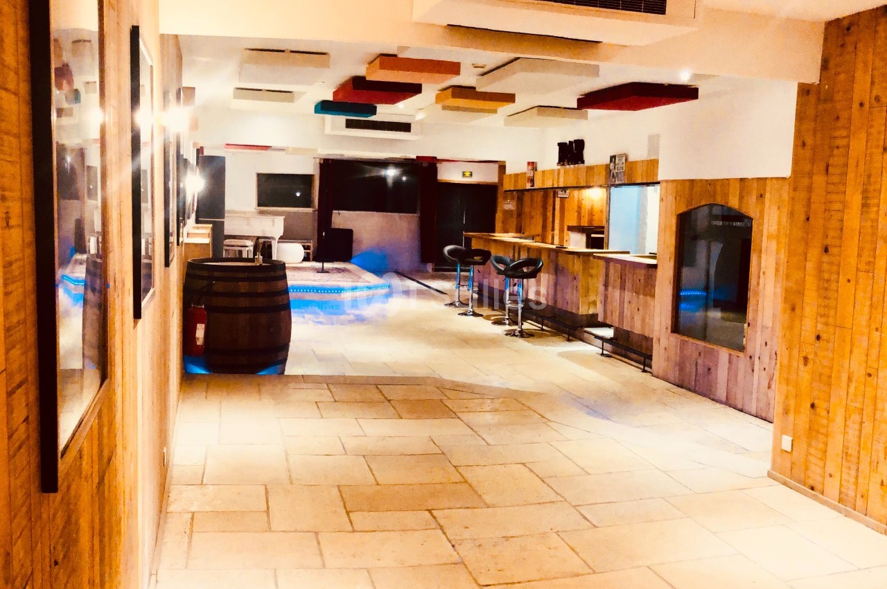 Couloir lumineux avec murs en bois, bar avec tabourets à droite et plafond décoré de panneaux colorés.