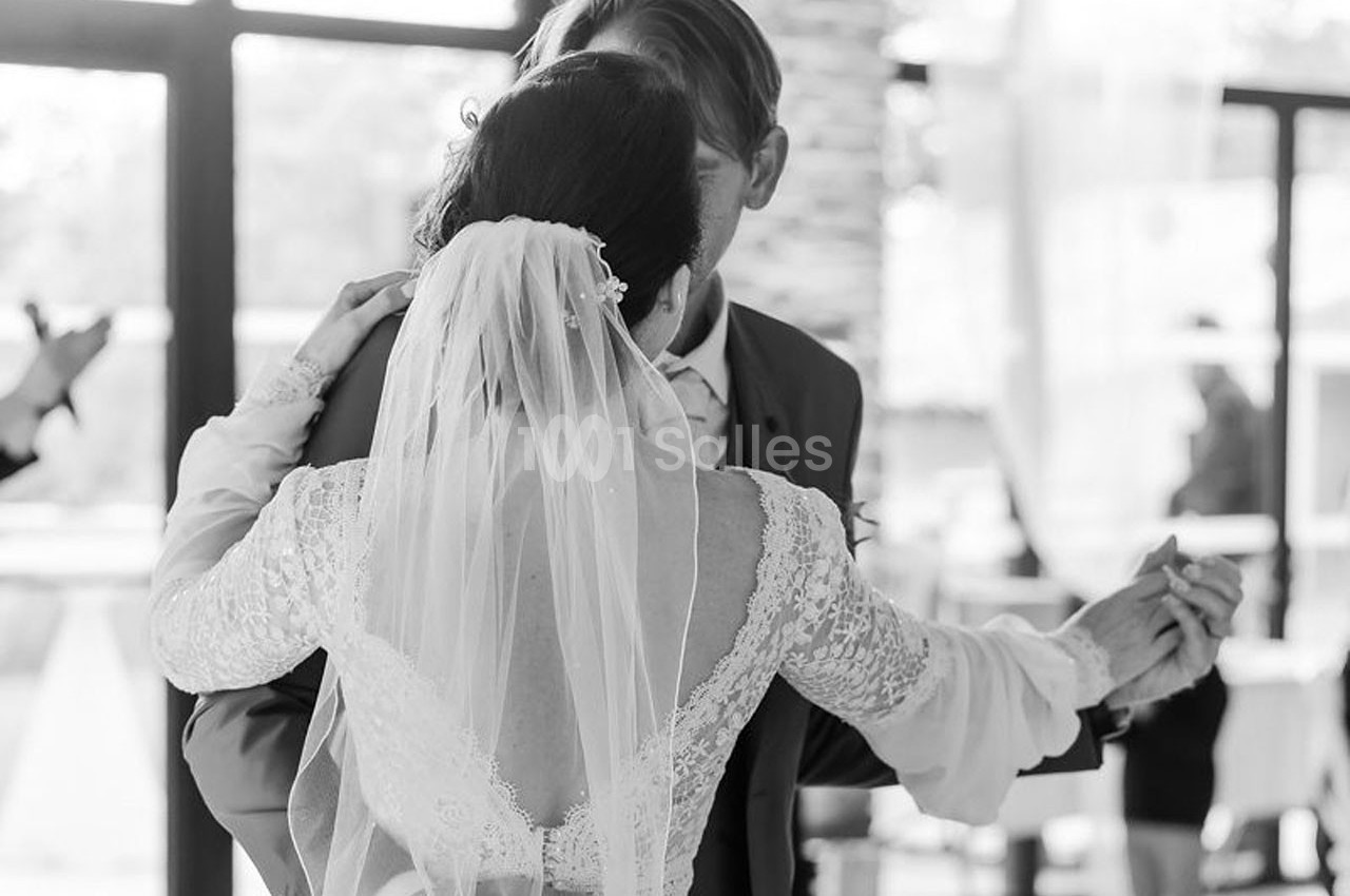 Un couple danse lors d'une cérémonie de mariage, la mariée portant un voile et une robe en dentelle.