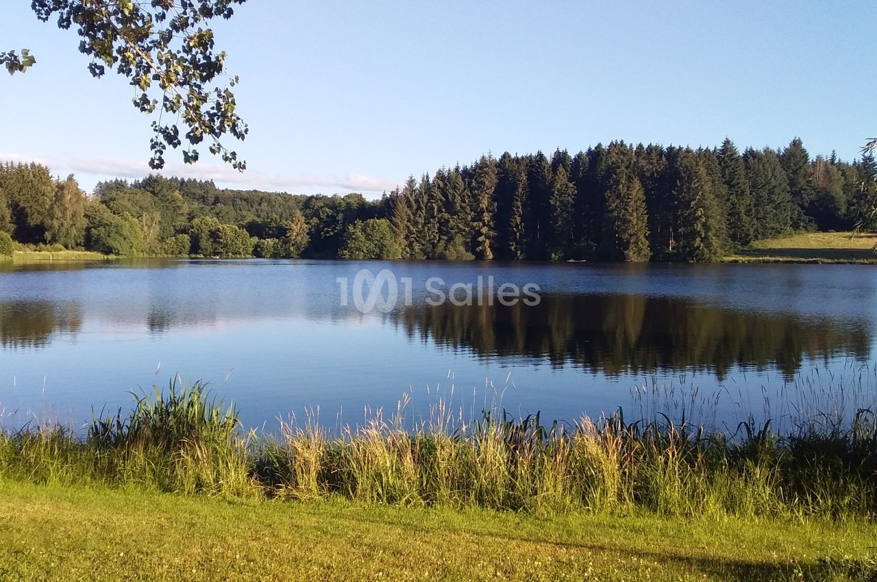 Vue d'un lac entouré de forêt et de végétation sous un ciel dégagé.