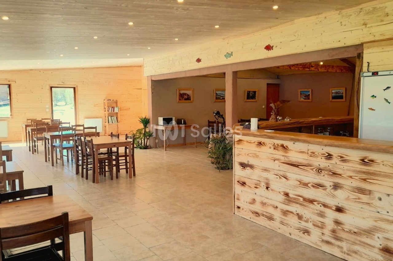 Salle lumineuse avec tables en bois, comptoir en bois clair et décoration murale simple.