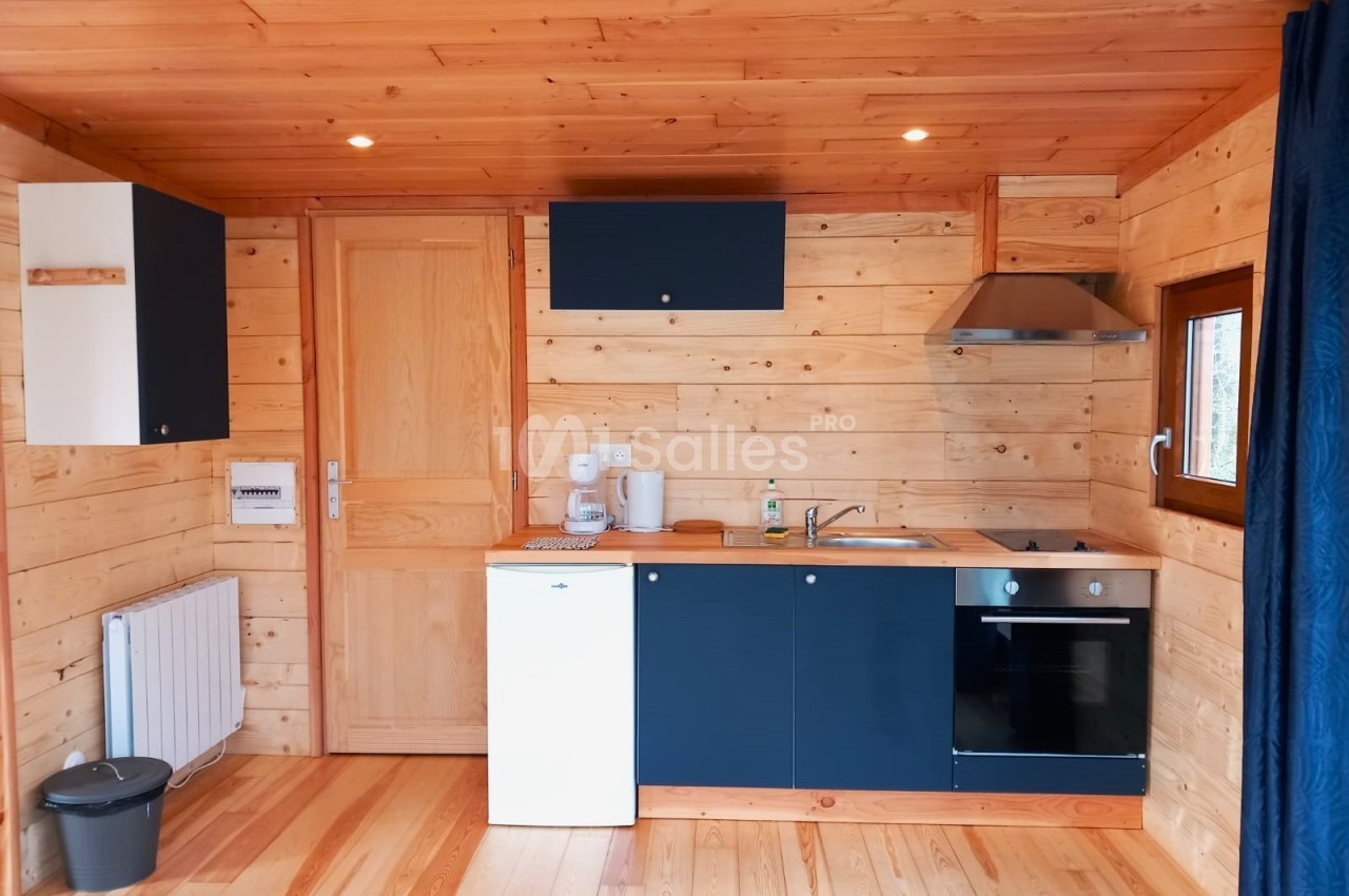 Cuisine en bois clair avec équipements modernes, comprenant un évier, une plaque de cuisson, un four et des rangements.