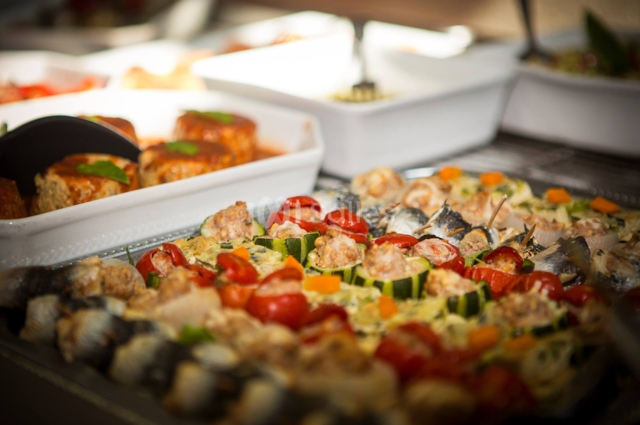 Plateau de plats variés comprenant des légumes grillés, des sardines et des préparations à base de viande.