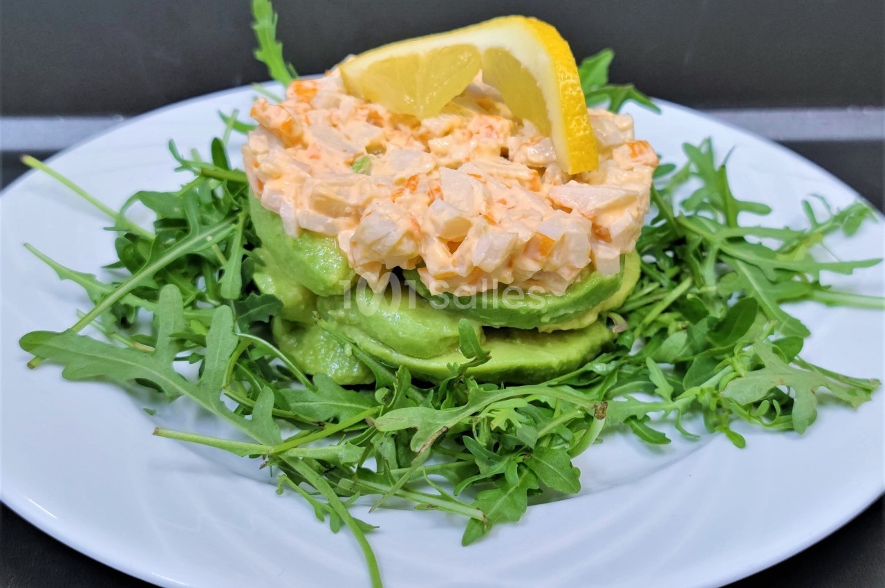 Assiette garnie de roquette, tranches d'avocat, mélange crémeux aux légumes et citron en décoration.