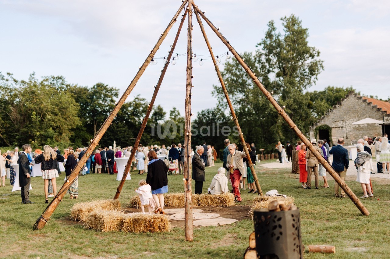 Des personnes rassemblées autour d'une structure en bois avec des bottes de foin, dans un cadre champêtre en plein air.