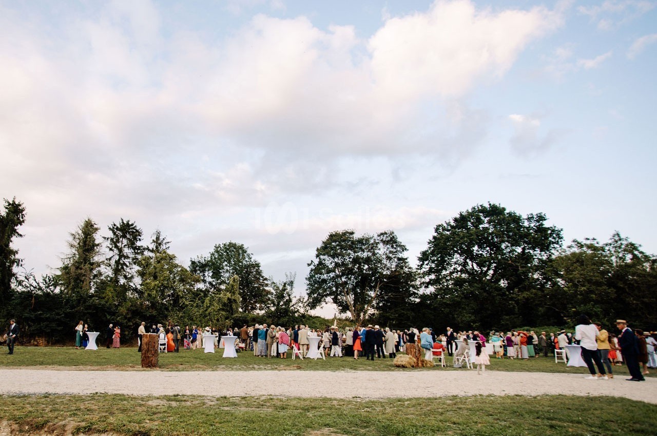 Groupe de personnes rassemblées en plein air dans un parc, sous un ciel partiellement nuageux.