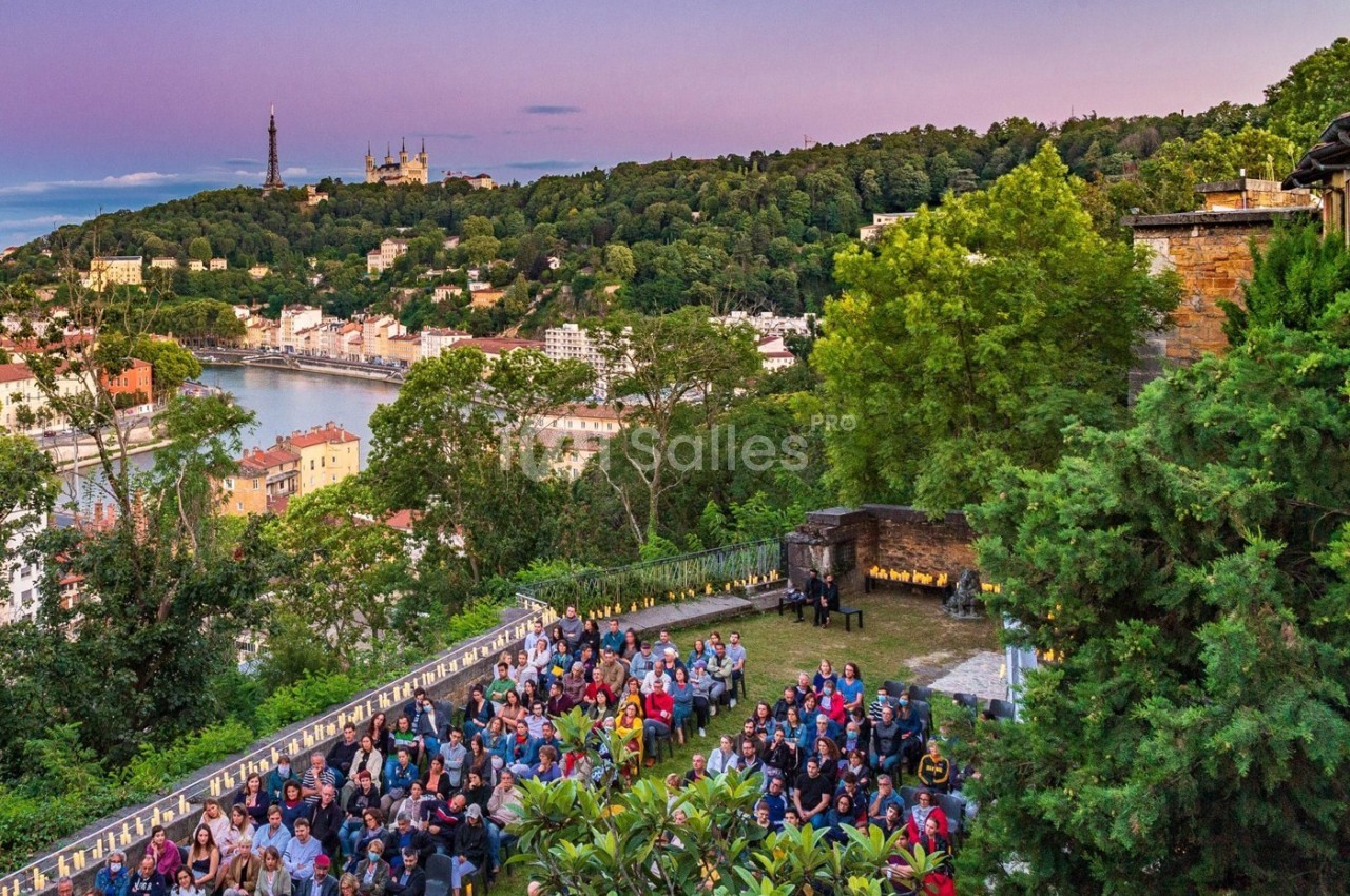 Vue d'un événement en plein air avec des participants, surplombant une ville, une rivière et des collines verdoyantes au…